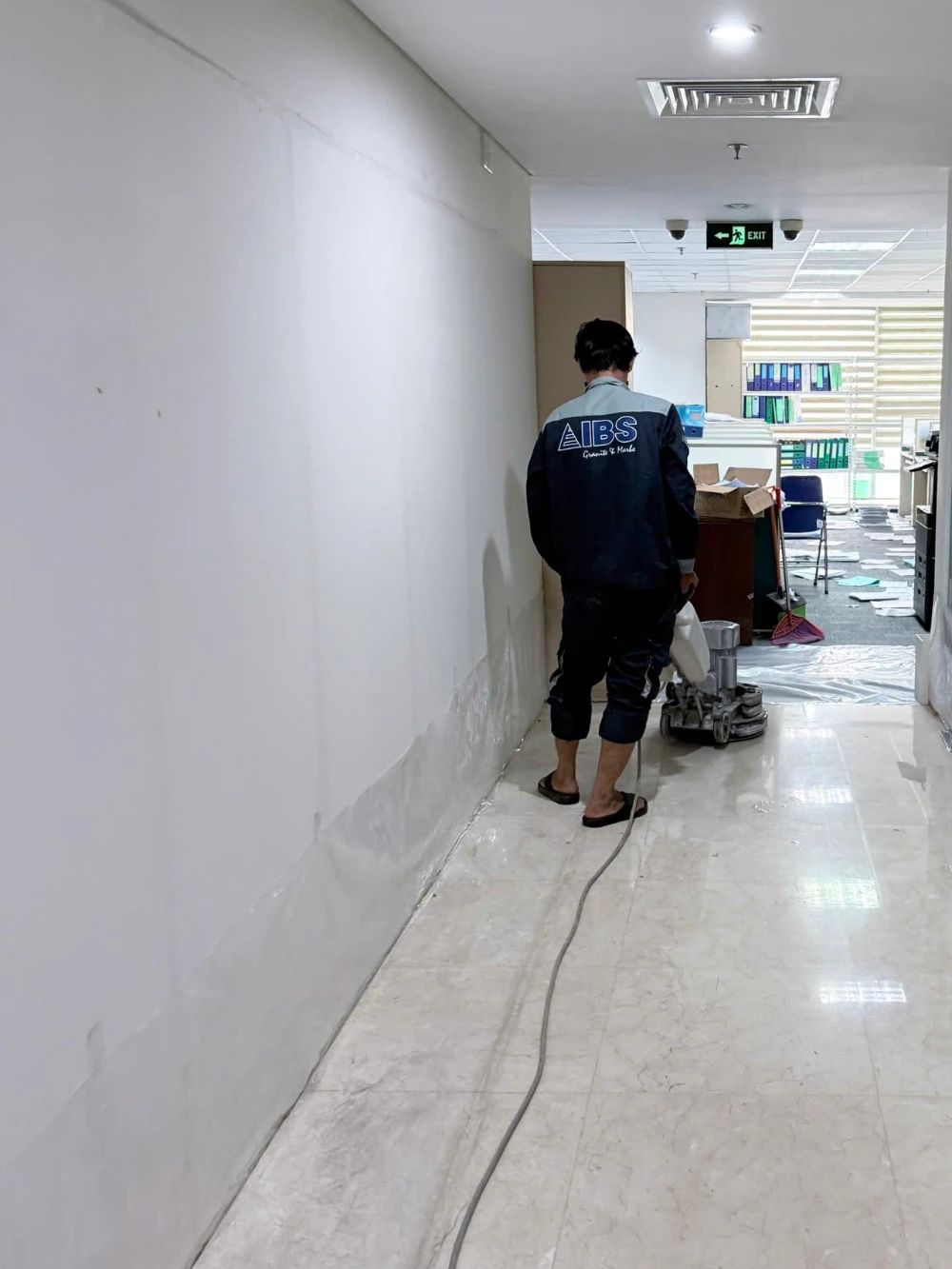 Thợ IBS mài sàn hành lang, chân tường đã được phủ nilon
